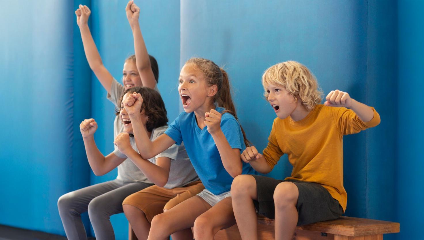 Kinderen juichen enthousiast vanaf de tribune tijdens een sportwedstrijd